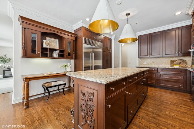 kitchen with built in fridge, a kitchen island, hanging light fixtures, light stone counters, and dark wood-type flooring