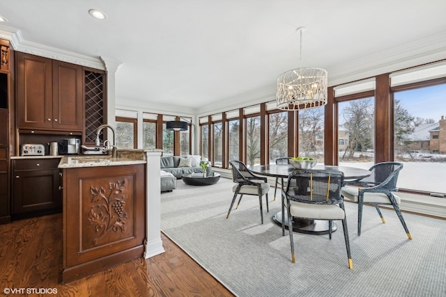 dining area with crown molding, plenty of natural light, dark hardwood / wood-style floors, and an inviting chandelier