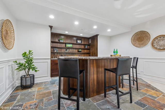 bar featuring dark brown cabinetry and ornamental molding