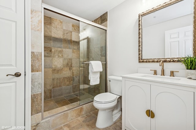 bathroom featuring vanity, a shower with door, and toilet