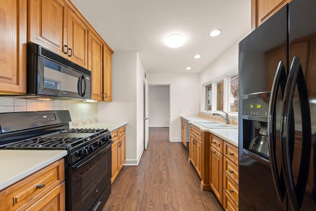 kitchen featuring light countertops, a sink, backsplash, and black appliances