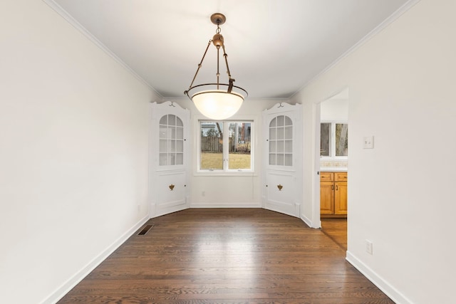 unfurnished dining area featuring dark wood-style floors, visible vents, ornamental molding, and baseboards