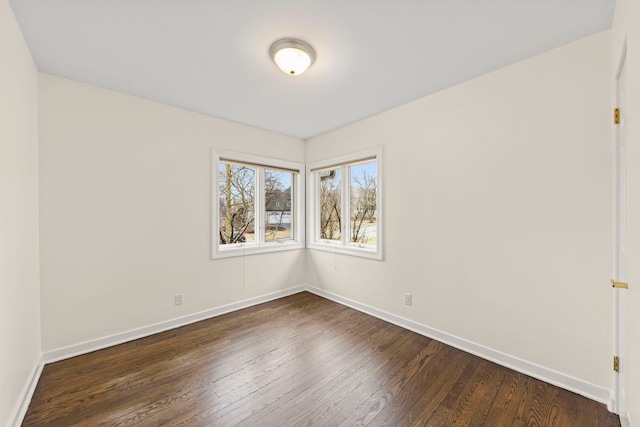 empty room featuring dark wood-style flooring and baseboards