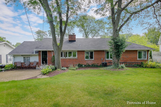 back of property featuring a patio, cooling unit, brick siding, a lawn, and a chimney