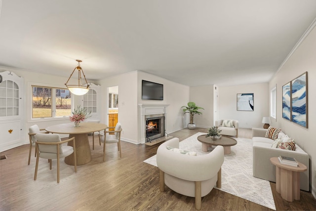 living area featuring a premium fireplace, visible vents, wood finished floors, and ornamental molding