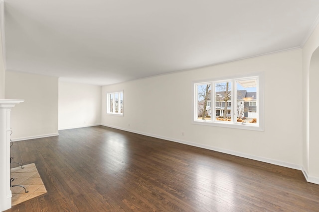 unfurnished living room with baseboards, arched walkways, and dark wood-type flooring