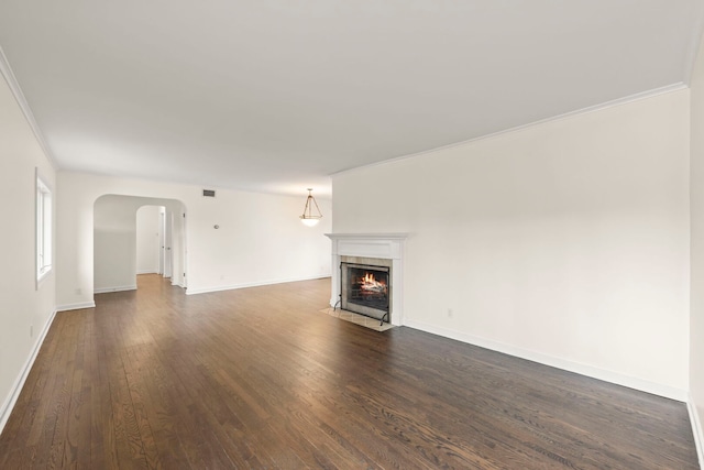 unfurnished living room with arched walkways, a fireplace, visible vents, baseboards, and dark wood finished floors