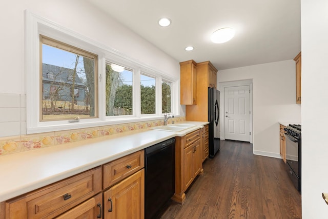 kitchen with dark wood finished floors, brown cabinets, light countertops, black appliances, and a sink