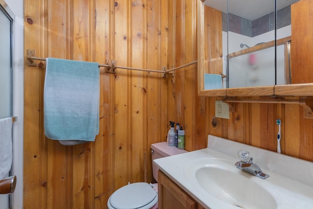 bathroom with vanity, an enclosed shower, wooden walls, and toilet