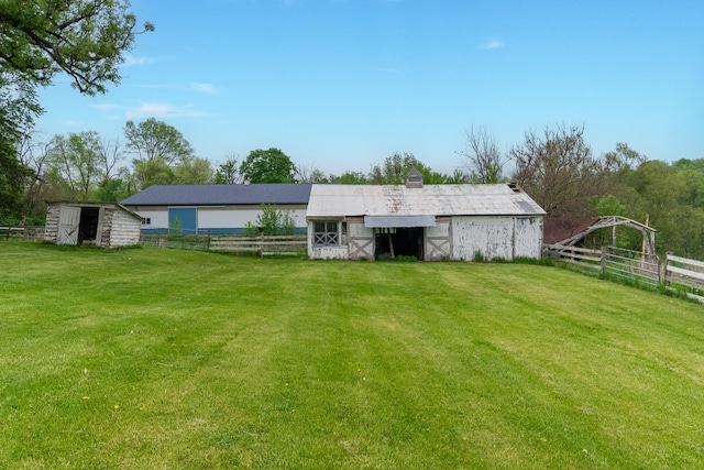 rear view of house with an outdoor structure and a lawn