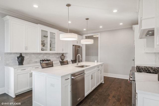 kitchen featuring stainless steel appliances, an island with sink, pendant lighting, and white cabinets