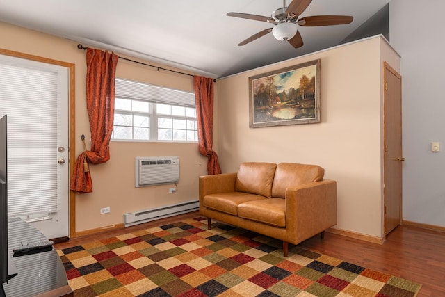 sitting room featuring baseboard heating, baseboards, dark wood finished floors, a ceiling fan, and an AC wall unit