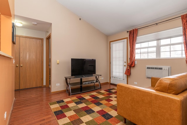 living room featuring wood finished floors, baseboards, vaulted ceiling, and a wall mounted AC