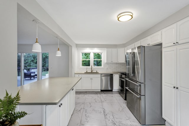 kitchen featuring appliances with stainless steel finishes, sink, pendant lighting, and white cabinets