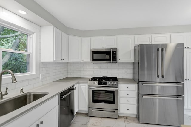 kitchen with white cabinetry, appliances with stainless steel finishes, sink, and decorative backsplash