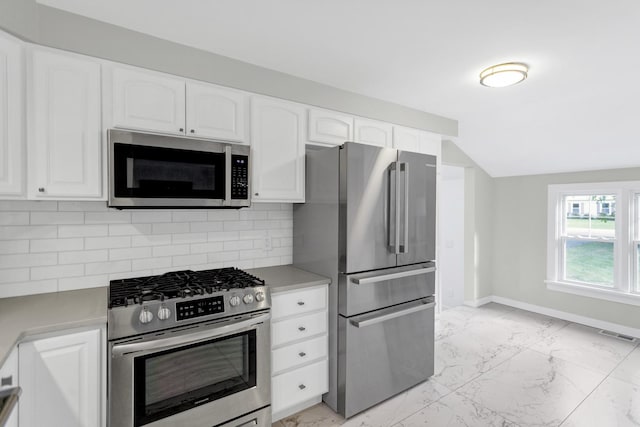 kitchen with backsplash, white cabinets, and appliances with stainless steel finishes