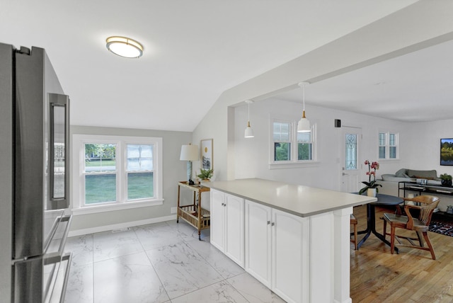 kitchen with pendant lighting, plenty of natural light, high end refrigerator, and white cabinets