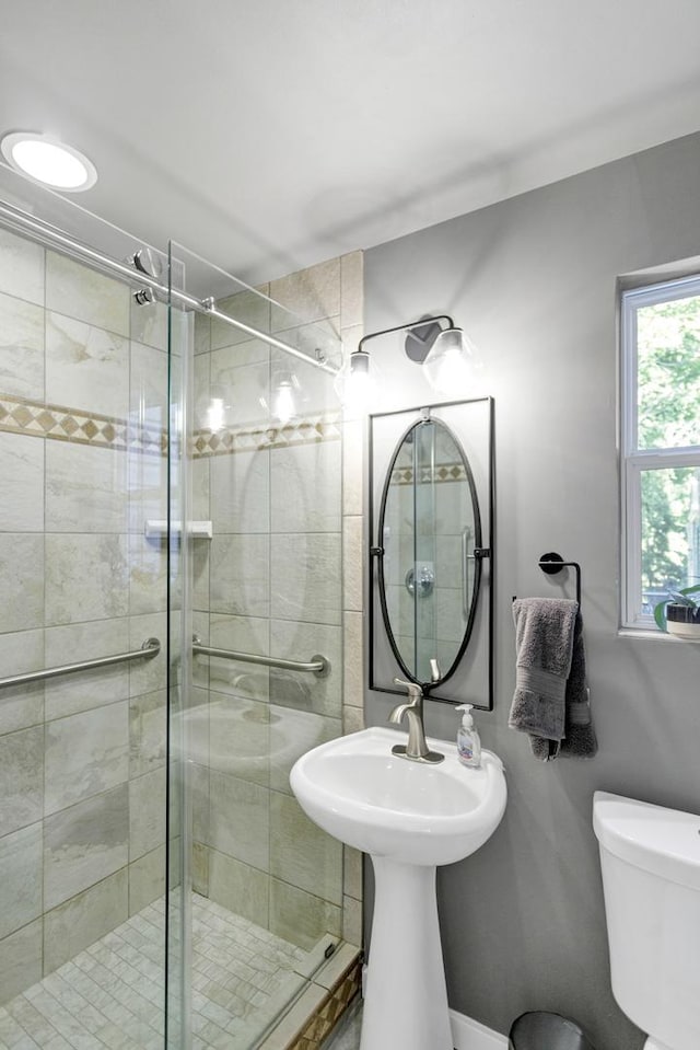 bathroom featuring a shower with door and toilet