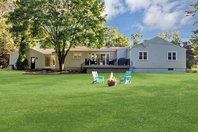 back of property with a wooden deck, a lawn, and an outdoor fire pit