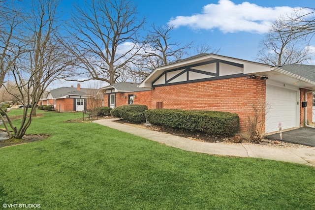 view of side of property featuring brick siding, a yard, driveway, and an attached garage