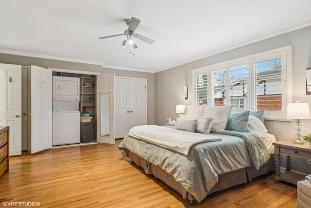 bedroom featuring light wood finished floors, multiple closets, ornamental molding, ceiling fan, and stacked washing maching and dryer