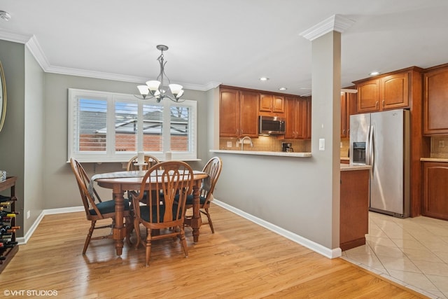 dining area featuring an inviting chandelier, light wood-style flooring, ornamental molding, and baseboards