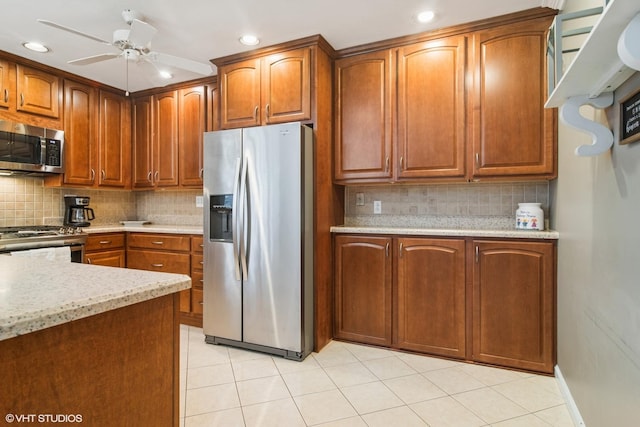 kitchen featuring appliances with stainless steel finishes, brown cabinets, backsplash, and a ceiling fan