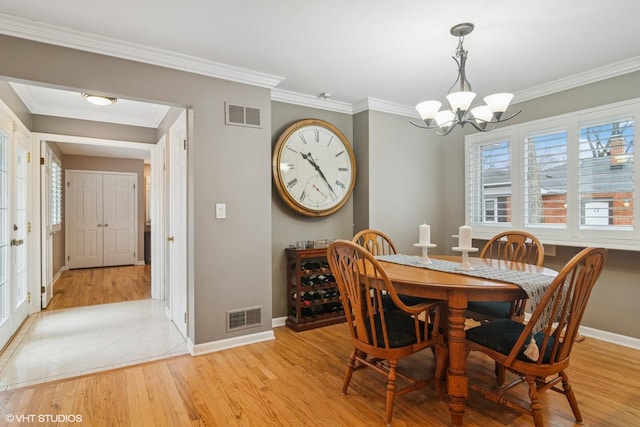 dining room featuring baseboards, visible vents, light wood finished floors, and an inviting chandelier