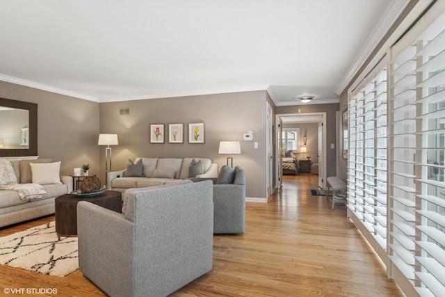 living area featuring visible vents, baseboards, light wood-style flooring, and crown molding