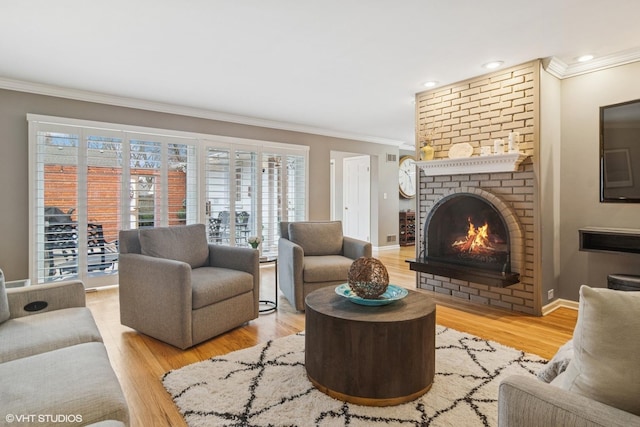 living area with light wood-type flooring, a brick fireplace, baseboards, and ornamental molding