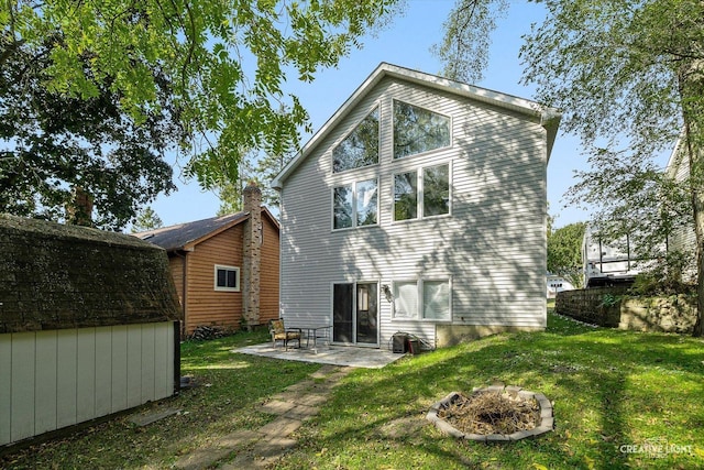 back of house with a yard, an outdoor fire pit, a patio, and a storage unit