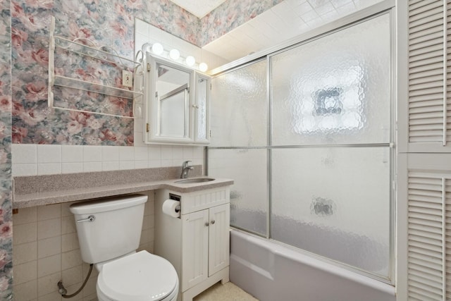 full bathroom with vanity, tile walls, shower / bath combination with glass door, and toilet