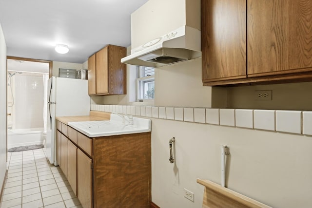 kitchen with sink, white refrigerator, and light tile patterned flooring