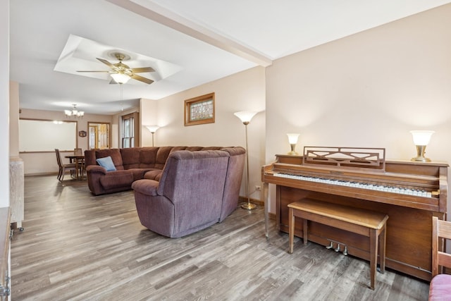 living room featuring beamed ceiling, ceiling fan with notable chandelier, and hardwood / wood-style floors