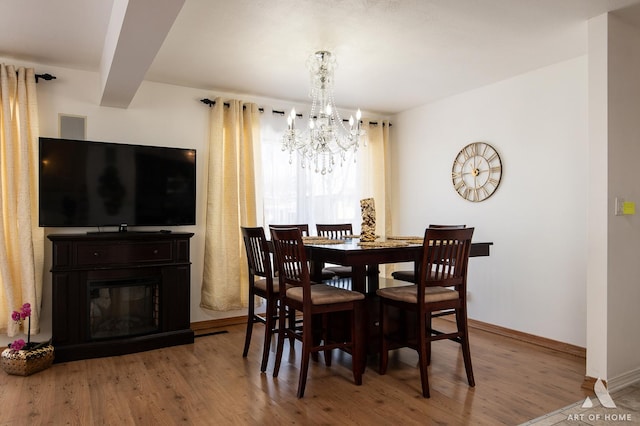 dining space with wood-type flooring, beam ceiling, and a notable chandelier