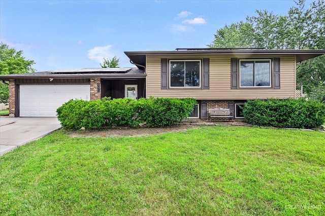 split level home featuring a garage, a front lawn, and solar panels