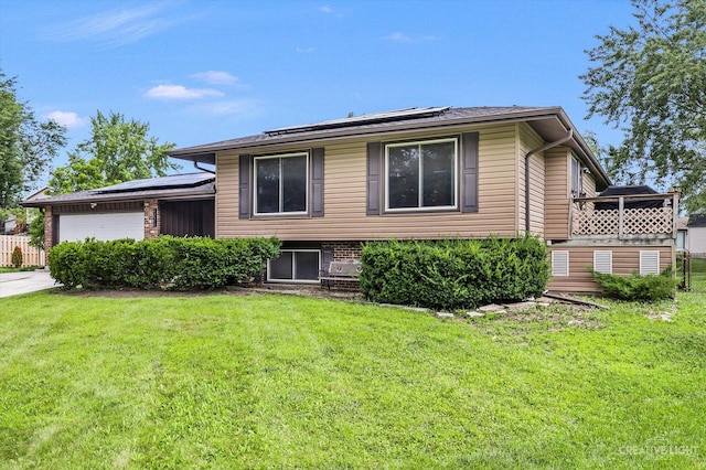 tri-level home with a garage, a front lawn, and solar panels