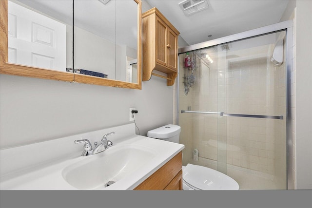 bathroom featuring vanity, a shower with door, and toilet