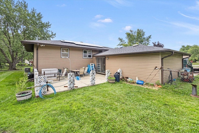 back of property with a lawn, a patio, and solar panels