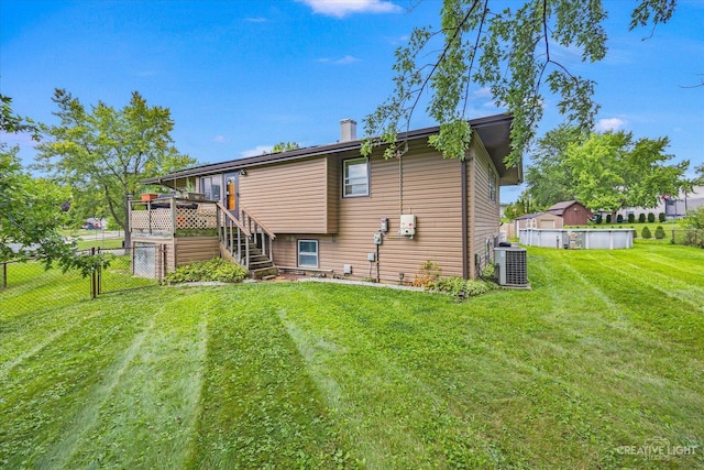 rear view of property with a pool side deck, central AC, and a lawn