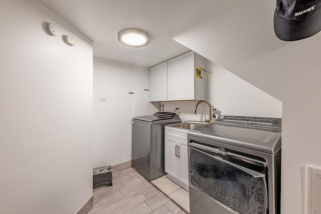 laundry room featuring cabinets, washer and clothes dryer, and sink