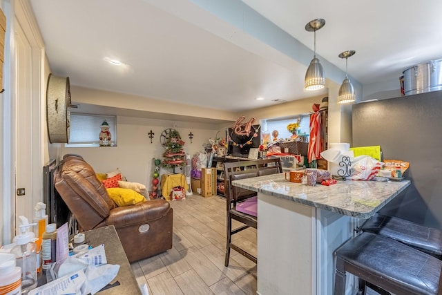 kitchen with hanging light fixtures, light stone countertops, a breakfast bar, and kitchen peninsula