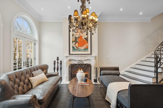 living room featuring dark hardwood / wood-style floors, a chandelier, ornamental molding, a high end fireplace, and french doors