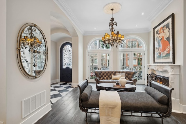 living room with ornamental molding, an inviting chandelier, dark hardwood / wood-style flooring, and french doors