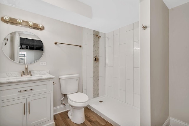 bathroom featuring vanity, wood-type flooring, toilet, and tiled shower