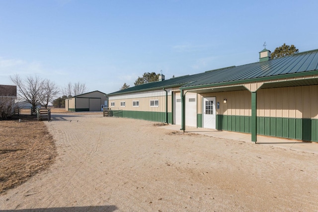 rear view of property featuring metal roof and an outbuilding