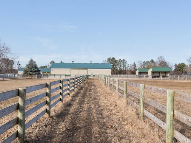 view of yard with a pole building, an enclosed area, an outbuilding, and a rural view