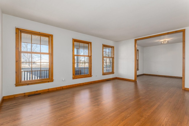 unfurnished room featuring visible vents, baseboards, and wood finished floors