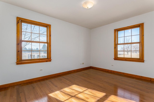 empty room with visible vents, baseboards, and hardwood / wood-style floors