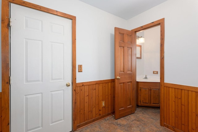 interior space with a wainscoted wall, a sink, and wooden walls